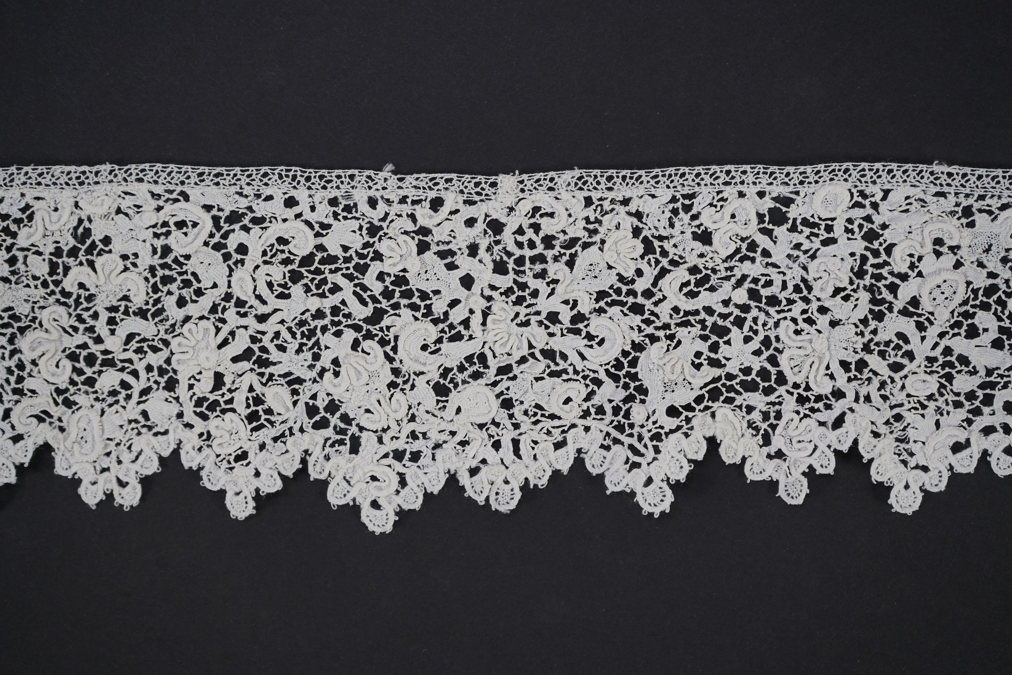 A late 17th century wide flounce of Point de France needle lace, together with a narrower flounce, both with raised elements of the design in the style of Point de Rose, but less so. This lace was very popular with the F